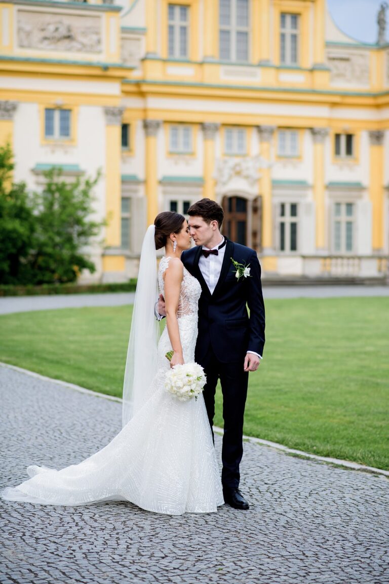 Nowożeńcy pozujący do sesji ślubnej pod pałacem w Wilanowie w Warszawie